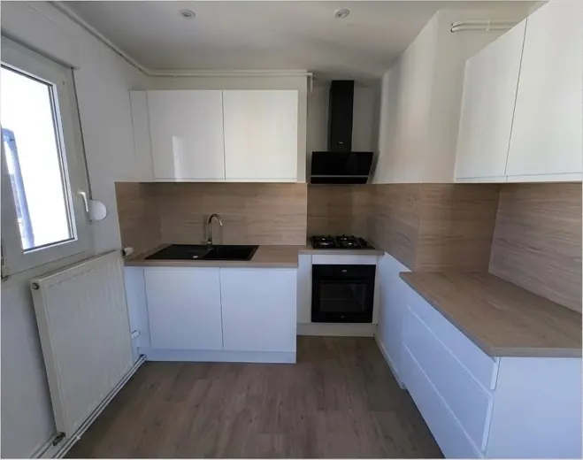 Cuisine après rénovation, avec meubles blancs et revêtement de sol effet bois