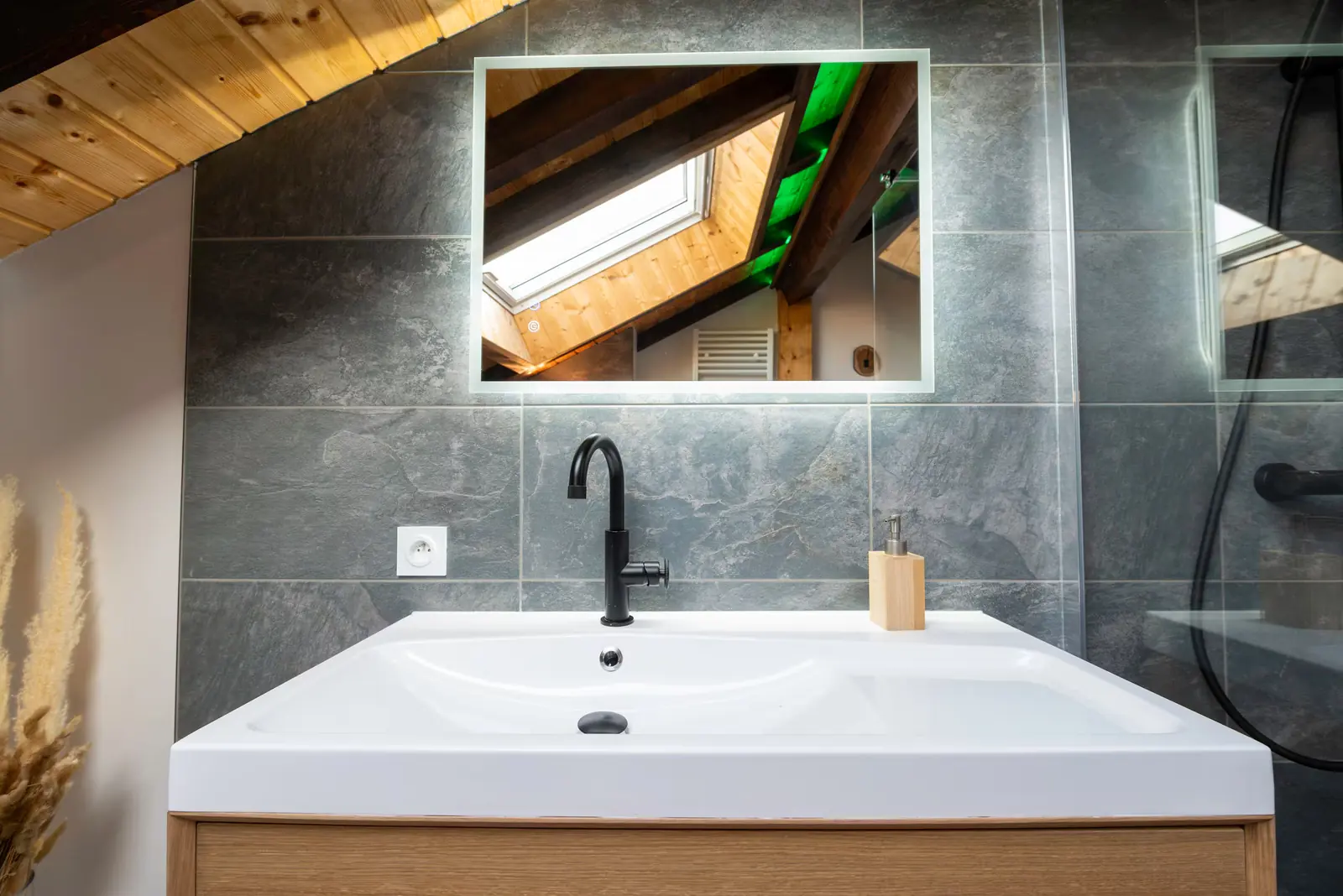 Salle de bain rénovée avec vasque blanche, robinet noir, miroir et carrelage gris